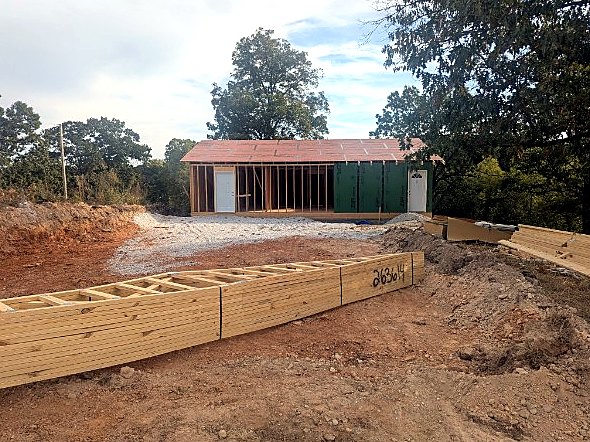 Corner of the house with lumber staged on site