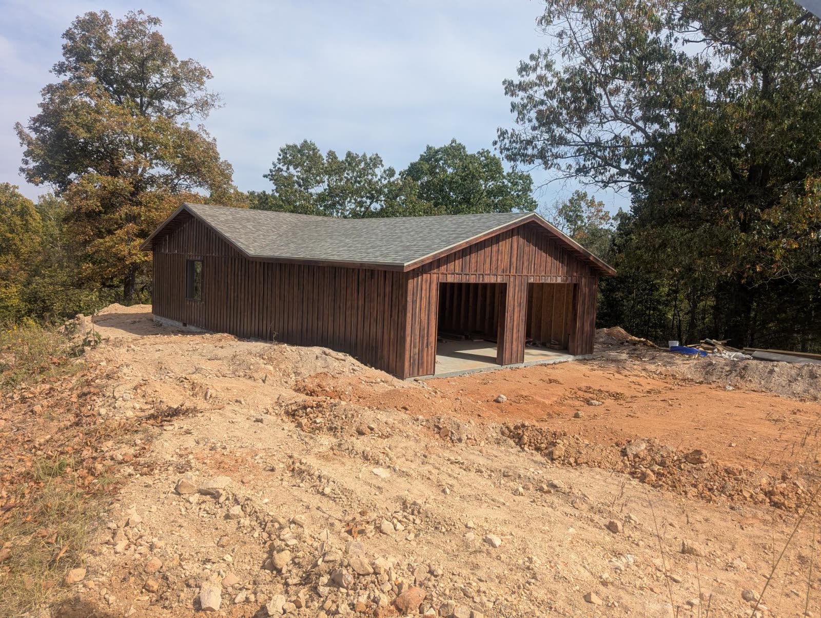 Garage side with wood siding, small window, and open bays