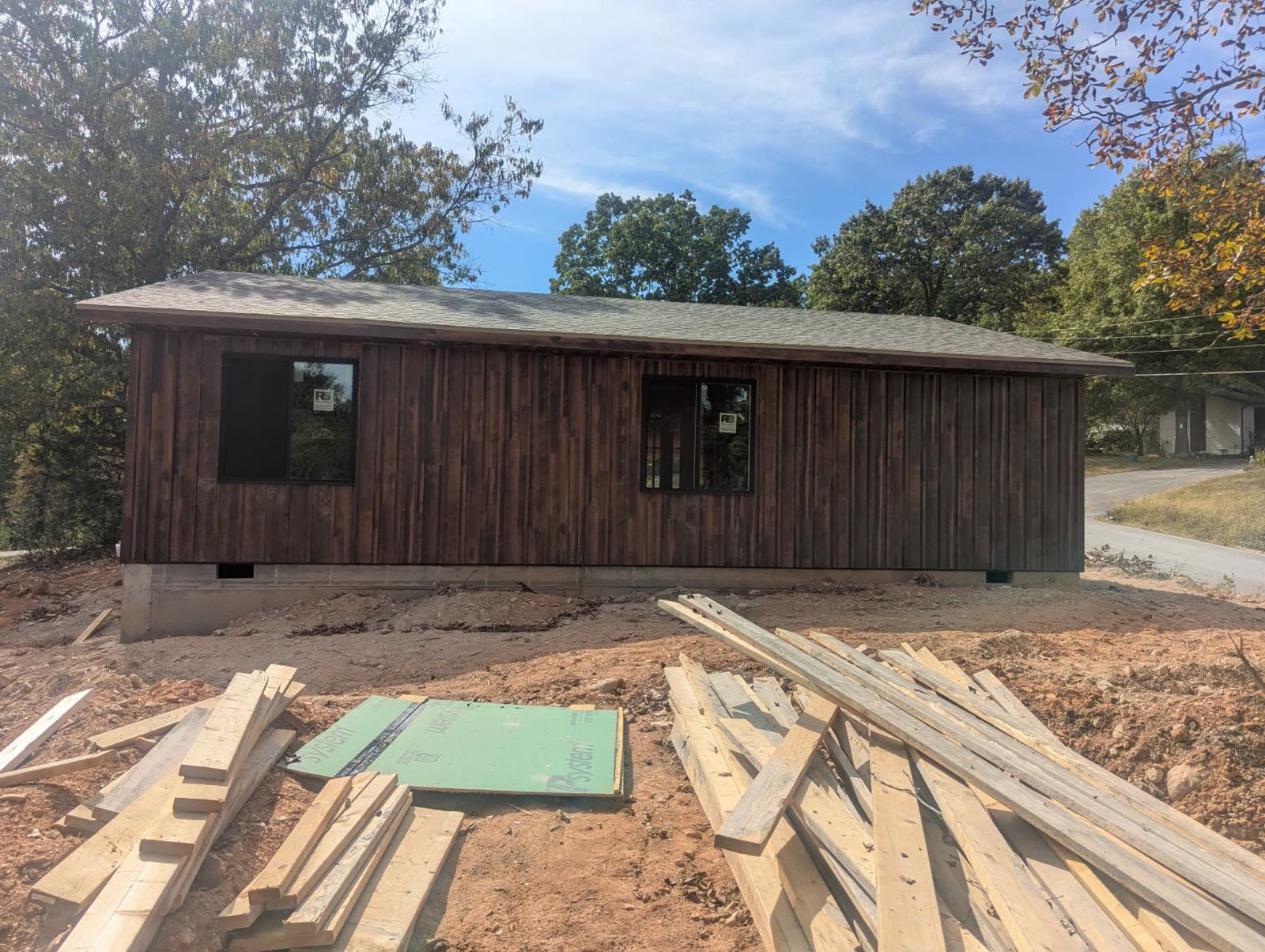Side of the house from the yard, windows in, lumber on site