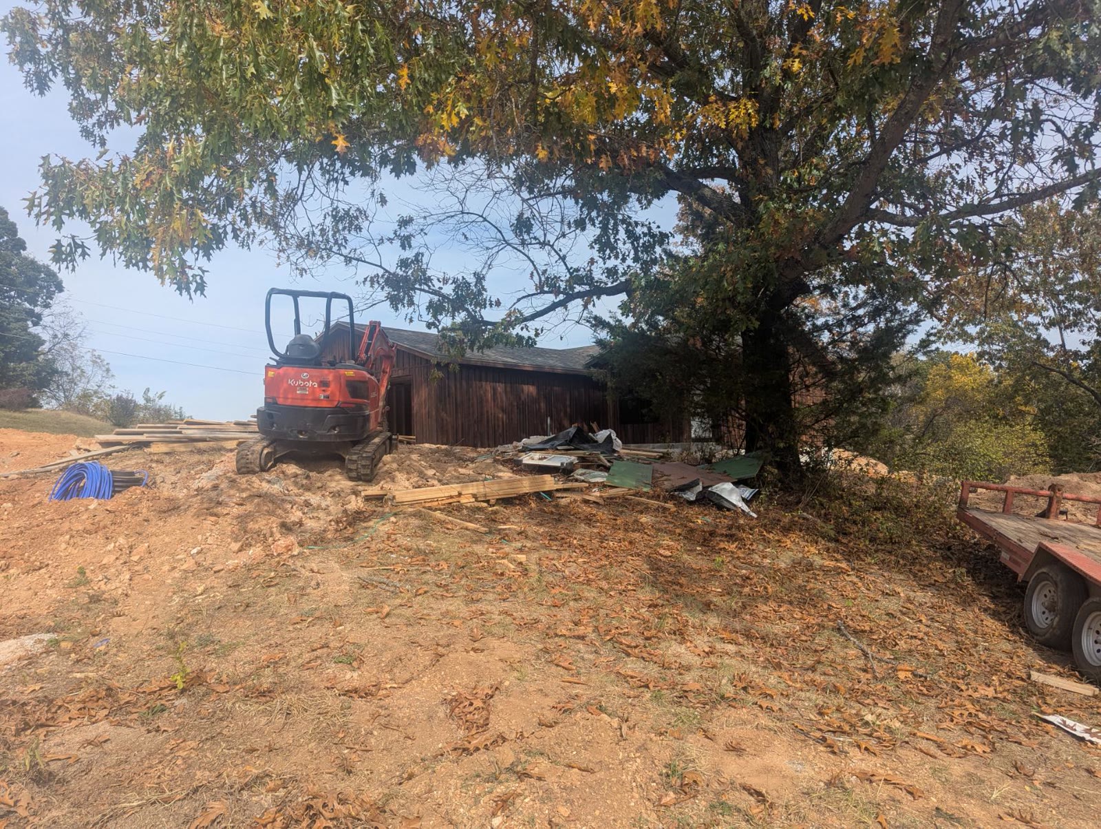 Excavator parked beside the house under the oak trees